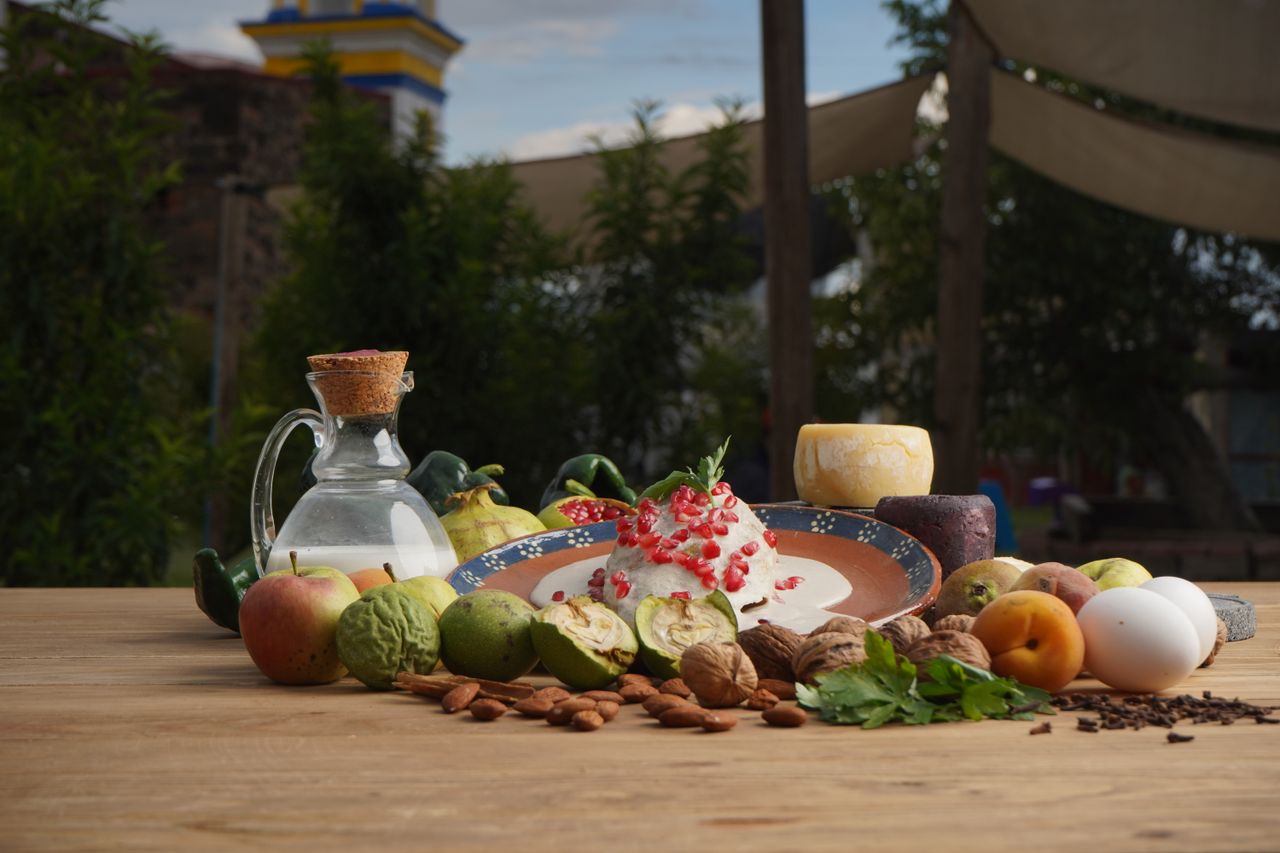 Services A rustic display of fruits, nuts, cheese, and more on a wooden table in an outdoor setting, embodying freshness and nature.