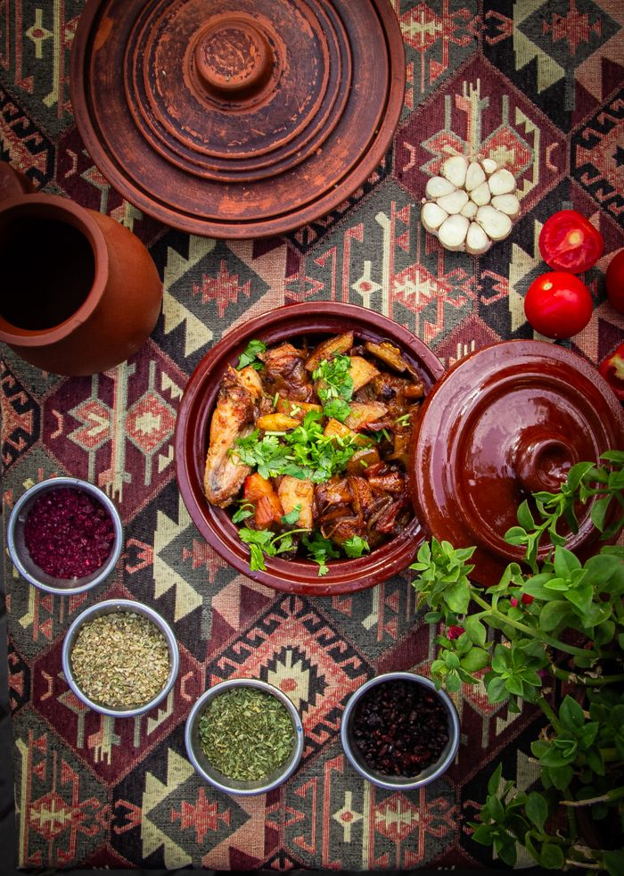 about-img Explore a vibrant display of traditional stew in rustic pottery surrounded by fresh herbs and spices.