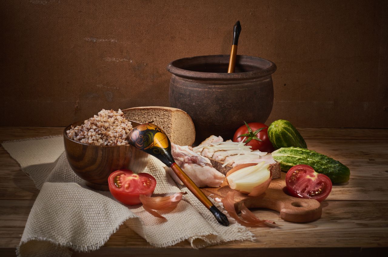 Home Cozy rustic still life featuring buckwheat, vegetables, and traditional tableware on a wooden surface.