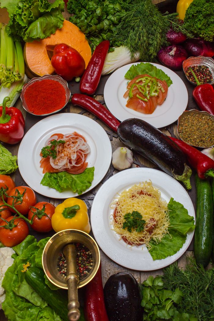 Colorful assortment of fresh organic vegetables and pasta dishes on a rustic table, ideal for healthy food concepts.
